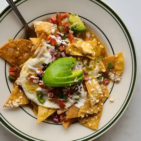 A plate of chilaquiles with a fried egg, avocado, pico de gallo, and sour cream.